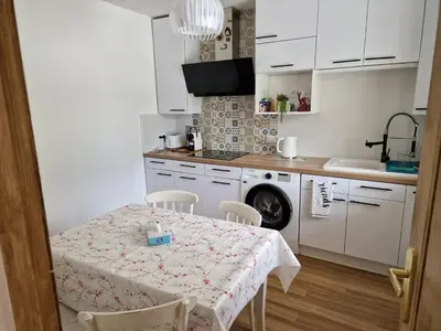 a white kitchen with a table and a sink at Villa BEETHOVEN in Carcassonne