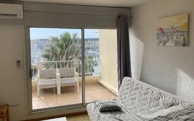 a living room with a view of a balcony with a couch at Vue ensoleillée sur le port de Gruissan in Gruissan