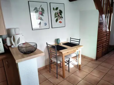 a kitchen with a table and two chairs and a table at Confortable maison de village en pierre typique in Molitg les Bains