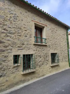 a stone building with three windows on it at Confortable maison de village en pierre typique in Molitg les Bains