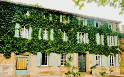 a building covered in ivy on a street at Maison d'hôtes de charme 