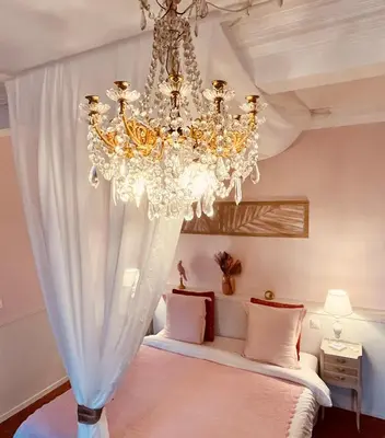 a bedroom with a large chandelier and a bed at Maison d'hôtes de charme 