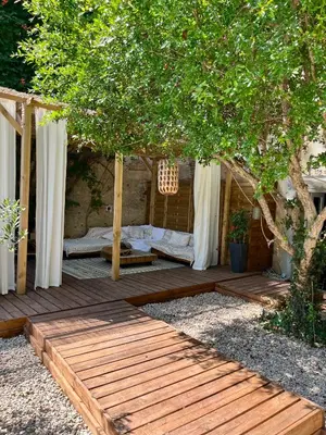 a wooden deck with a bed under a tree at Maison d'hôtes de charme 