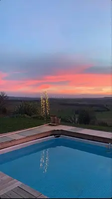 a swimming pool with a sunset in the background at Villa avec piscine à débordement vue exceptionnelle in Puéchoursi