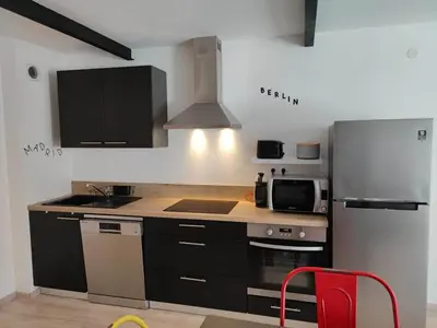 a kitchen with a stainless steel refrigerator and a red chair at La Bastide de Gabin / ConciergerieDameCarcas in Carcassonne