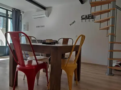 a dining room table with two chairs and a staircase at La Bastide de Gabin / ConciergerieDameCarcas in Carcassonne