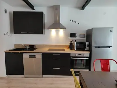 a kitchen with black cabinets and a stove and refrigerator at La Bastide de Gabin / ConciergerieDameCarcas in Carcassonne