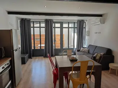 a living room with a table and chairs and a couch at La Bastide de Gabin / ConciergerieDameCarcas in Carcassonne