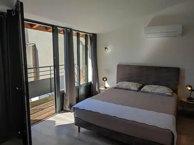 a bedroom with a bed and a balcony at La Bastide de Gabin / ConciergerieDameCarcas in Carcassonne