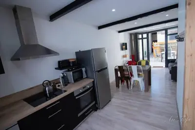 a kitchen with a stainless steel refrigerator and a living room at Le Gabin Moderne Loft in Carcassonne