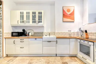 a kitchen with white cabinets and a sink at Au Puits de la Cité - Terrasse Vue Cité - Wifi in Carcassonne