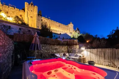a hot tub in front of a castle at night at Au Puits de la Cité - Terrasse Vue Cité - Wifi in Carcassonne