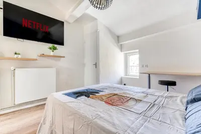 a bedroom with a bed with a tv on the wall at Côté Palais 2 avec Netflix - Fibre - Proche Cité in Carcassonne