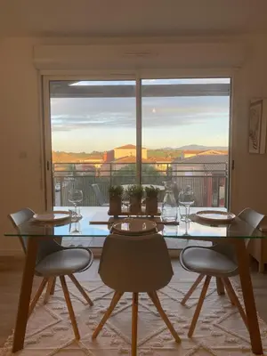 a dining room table with chairs and a large window at Appartement cosy, vue imprenable in Carcassonne