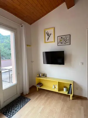 a living room with a tv and a yellow shelf at Cases des oliviers in Cases-de-Pène