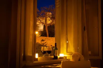 a window with two glasses of wine and candles at Le Pied à Terre de la Cité - Parking au Pied de la Cité in Carcassonne