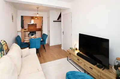 a living room with a white couch and a flat screen tv at Le Pied à Terre de la Cité - Parking au Pied de la Cité in Carcassonne