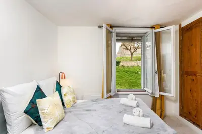 a bedroom with a bed with a window and towels at Le Pied à Terre de la Cité - Parking au Pied de la Cité in Carcassonne