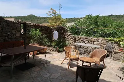 a patio with a table and chairs and a stone wall at La maison d' Anne , nature et convivialité ... in Albas