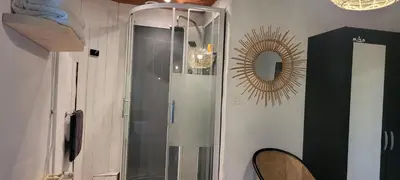 a shower with a glass door in a room with a mirror at LA CHAMBRE DU CANTOU in Lautrec