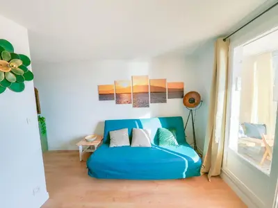 a blue couch in a room with a window at Splendide appartement GOLDEN HOUSE vue LAC et montagne in Port-la-Nouvelle