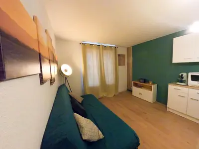 a living room with a green couch in a room at Splendide appartement GOLDEN HOUSE vue LAC et montagne in Port-la-Nouvelle