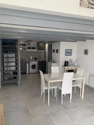 a dining room with a table and white chairs at L appart d Ange 2 idealement situe 47m2 entre le port et le village in Gruissan