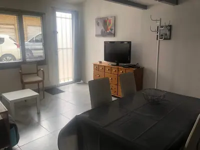 a living room with a dining table and a television at L appart d Ange 2 idealement situe 47m2 entre le port et le village in Gruissan