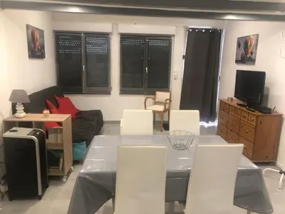 a living room with a table and white chairs at L appart d Ange 2 idealement situe 47m2 entre le port et le village in Gruissan