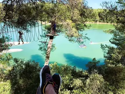 a person standing on a tree branch over a lake at Chambre Indépendante Piscine, Parc, Cuisine... in Brézilhac