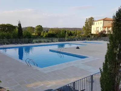 a large pool with blue water in a yard at Apartment in Azille near Lac de Jouarres in Azille