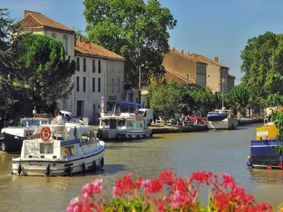 a group of boats docked in a river with flowers at Apartment in Azille near Lac de Jouarres in Azille
