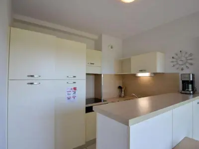 a kitchen with white cabinets and a white refrigerator at Apartment in Azille near Lac de Jouarres in Azille
