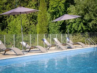 a row of chairs and umbrellas next to a swimming pool at Residence du Château de Jouarres, Azille - Studio 2 pers with balcony in Azille