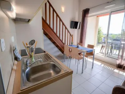 a kitchen with a sink and a dining room with a table at Residence du Château de Jouarres, Azille - Studio 2 pers with balcony in Azille