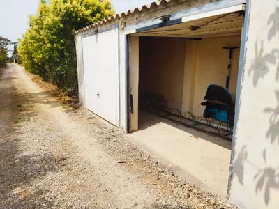 a garage with a door open on a dirt road at Aur Blan - Les Pipistrelles in Le Somail