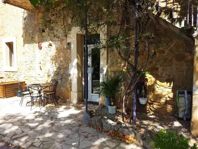 a stone house with a table and chairs outside at Aur Blan - Les Pipistrelles in Le Somail