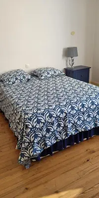 a bed in a bedroom with a blue and white bedspread at Le lorrain in Campagne-sur-Aude