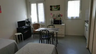 a room with a table and chairs and a kitchen at Résidence Anclo in Rennes-les-Bains