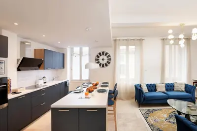 a kitchen and living room with a blue couch at L'art de Gambetta ConciergerieDameCarcas in Carcassonne
