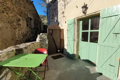 a green table and chairs next to a building with a door at Le Cantou de Juliette (studio) in Prugnanes