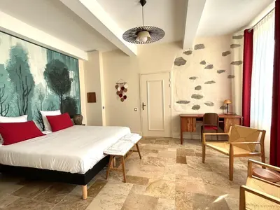 a bedroom with a bed and a table and chairs at Domaine de Lanis - Chambres d'hôtes avec parc et piscine in Castelnaudary