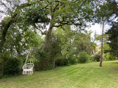 a white swing hanging from a tree in a yard at Domaine de Lanis - Chambres d'hôtes avec parc et piscine in Castelnaudary
