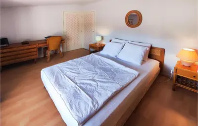 a bedroom with a large bed with a desk and a desk at 2 Bedroom Cozy Home In Cébazan in Cébazan