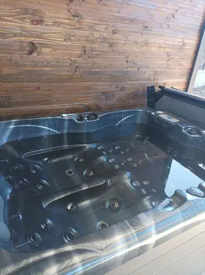 a bath tub in a room with a wooden wall at Loft sauna jacuzzi ospariegeois in Lavelanet