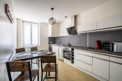 a kitchen with white cabinets and a table and chairs at L'appart cinéma Centre ville Narbonne in Narbonne