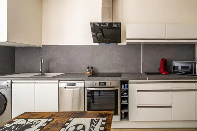 a kitchen with white cabinets and a stove top oven at L'appart cinéma Centre ville Narbonne in Narbonne