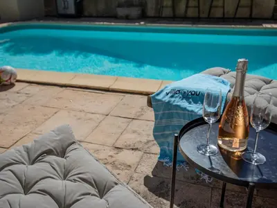 a bottle of champagne and two glasses on a table next to a swimming pool at Lécurie in Montréal