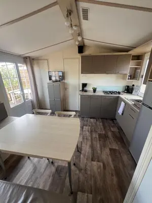a kitchen with a table in a room at Les mobil homes de NOLY TV CLIM 6places in Port-la-Nouvelle