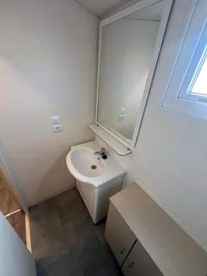 a white bathroom with a sink and a mirror at Les mobil homes de NOLY TV CLIM 6places in Port-la-Nouvelle